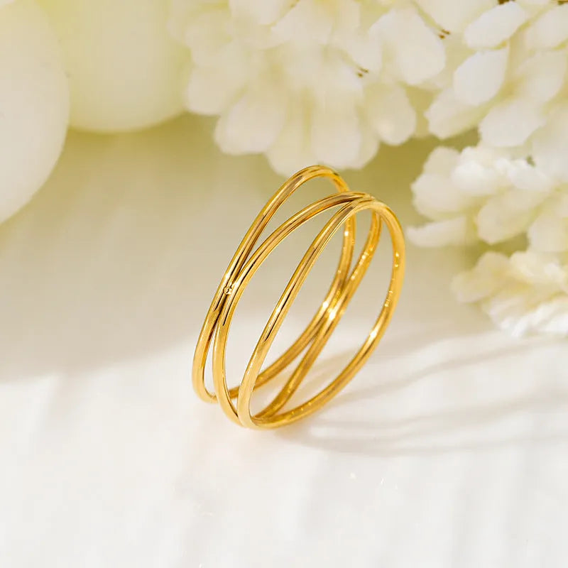 Gold-coloured geometric line ring with a three-layer coil design on a titanium steel band.