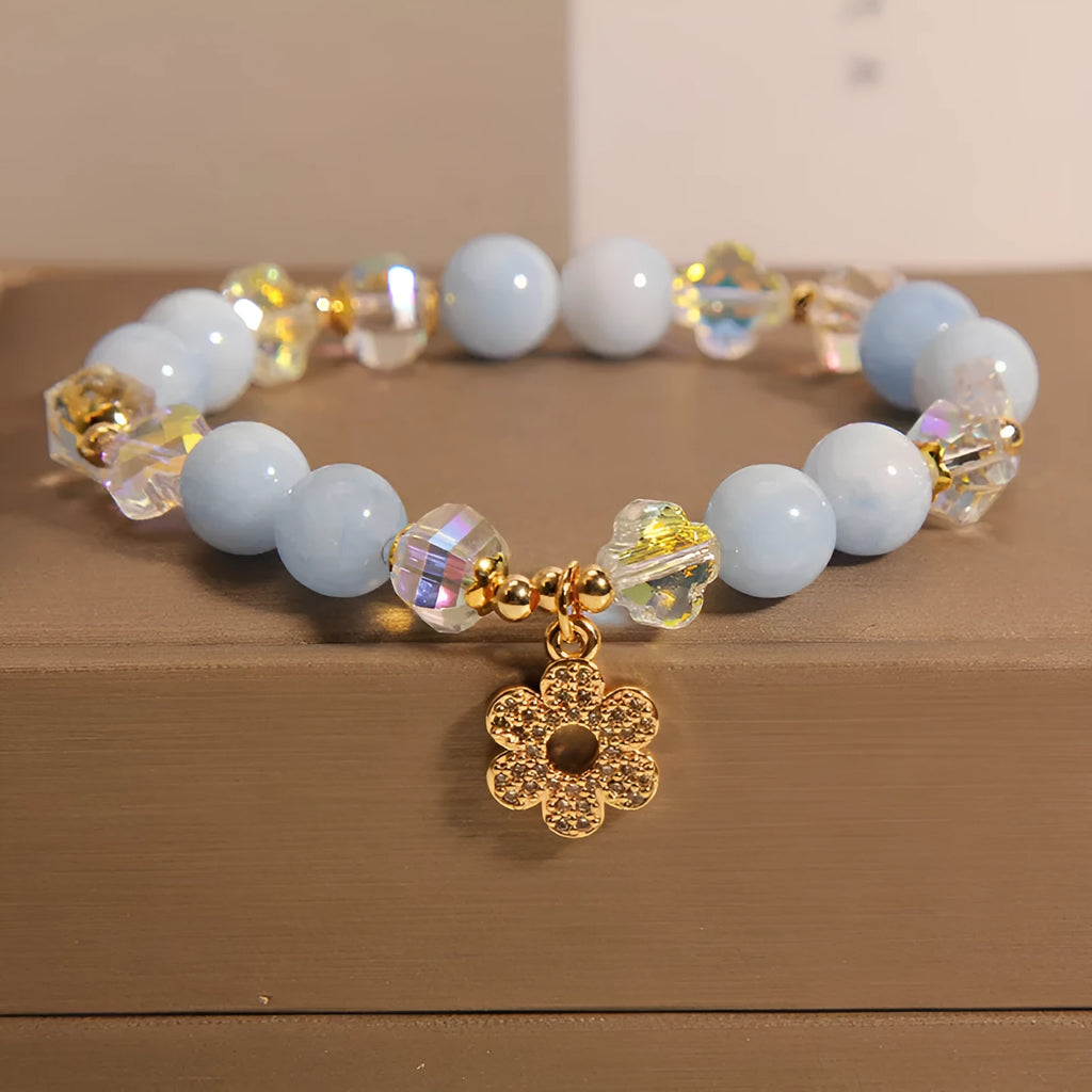 Aquamarine crystal and pearl bracelet with four-leaf clover charm on wrist.