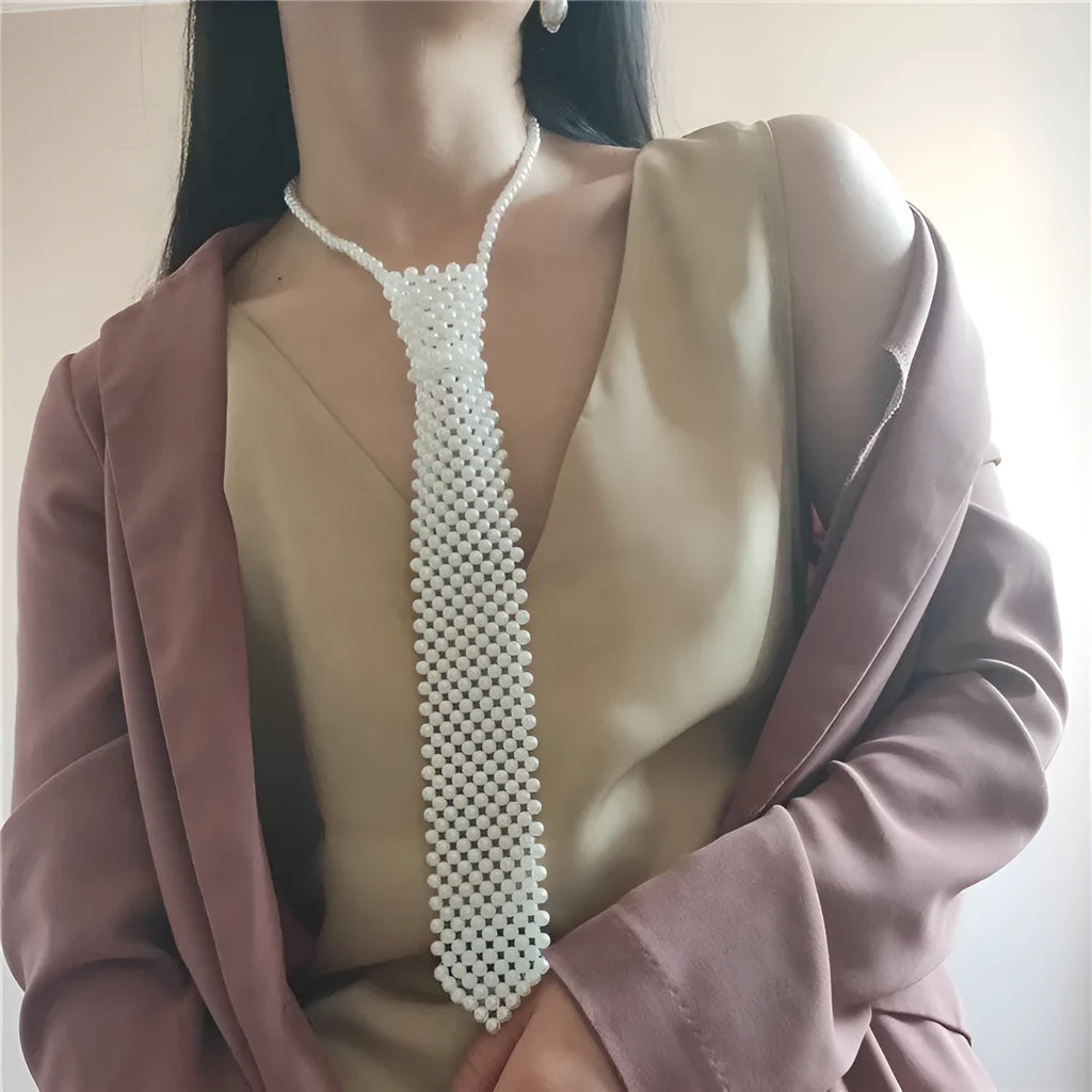 Close-up of a white imitation pearl body chain with an adjustable alloy tie clasp on a dark background.
