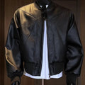Man wearing a black PU leather jacket with litchi grain texture, showcasing its 100cm extended length and light business style fit.