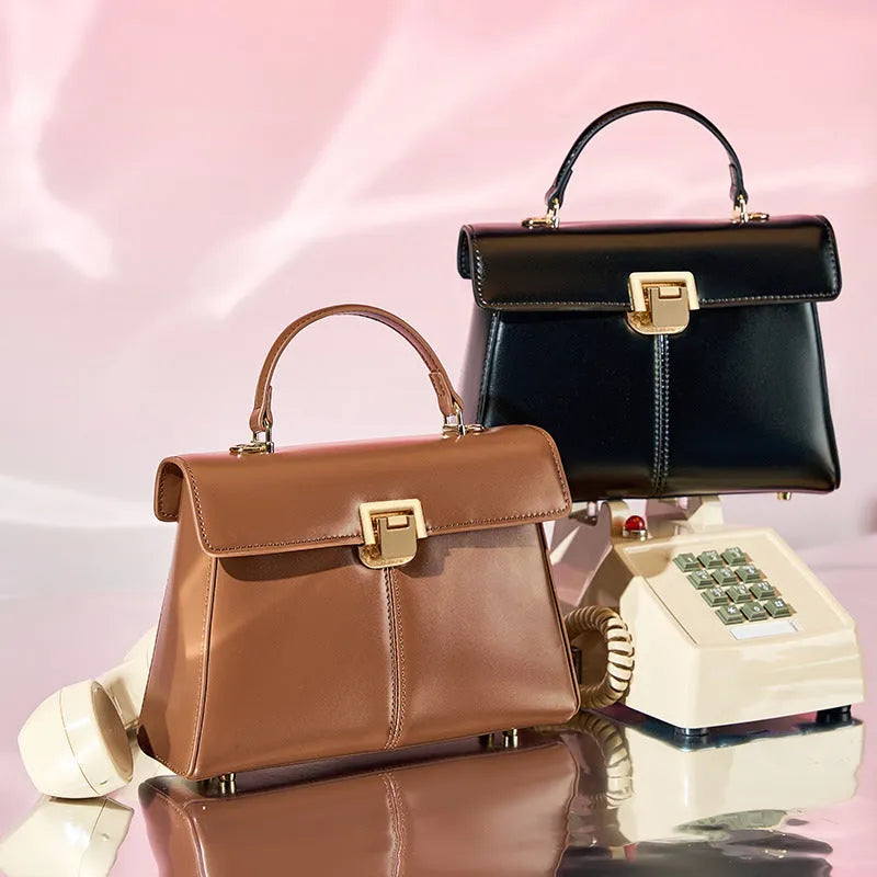 Black leather women's shoulder bag with clasp closure showing internal zippered compartment and adjustable strap