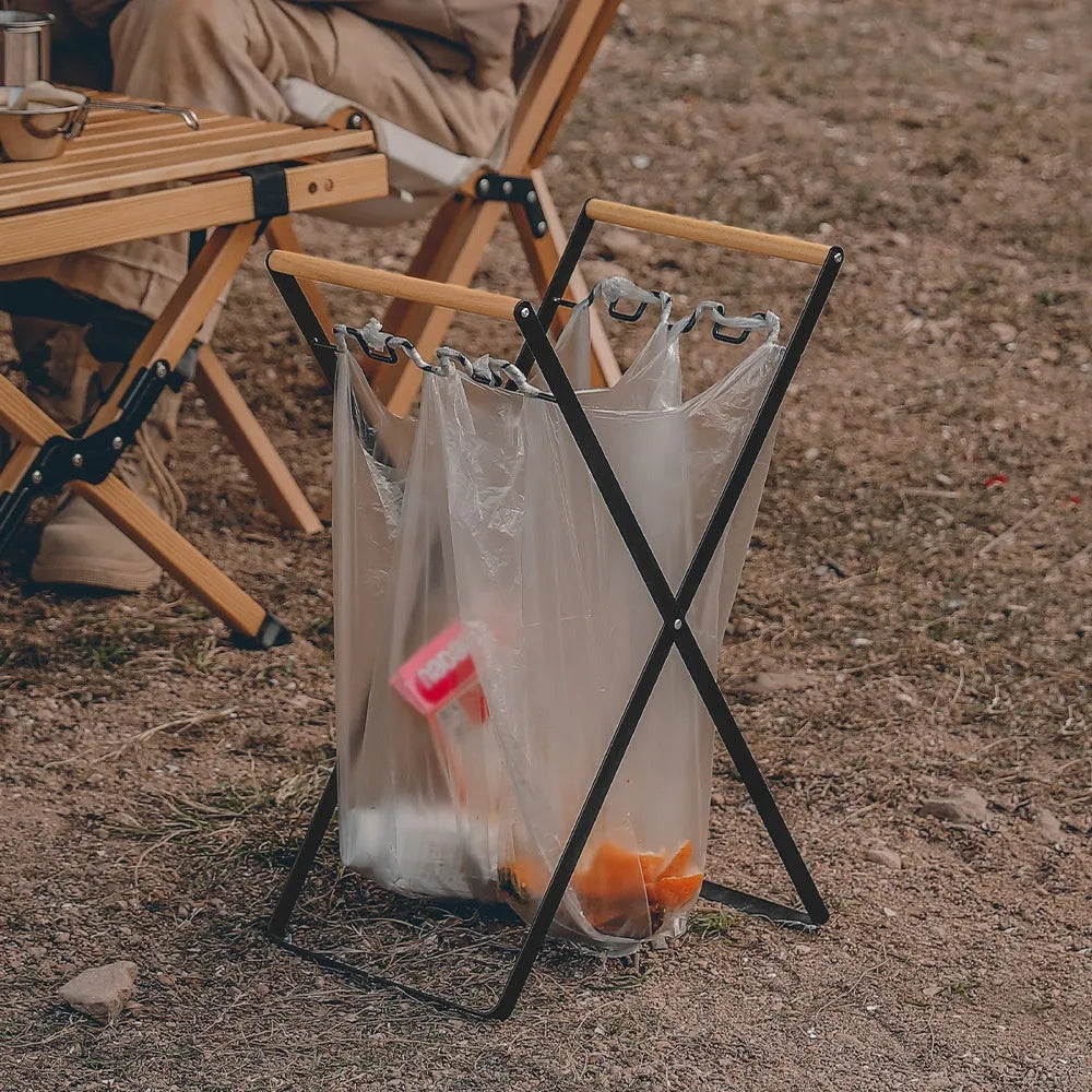 Black folding iron trash rack with wood handle holding bin bag outdoors