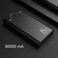 Black fast charging 20000mAh power bank with alloy shell and LED flashlight on a table.