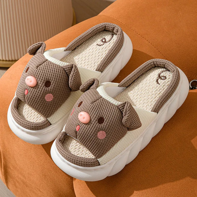 Pair of piggy cute open toe linen flip flop slippers for couples on a plain background.