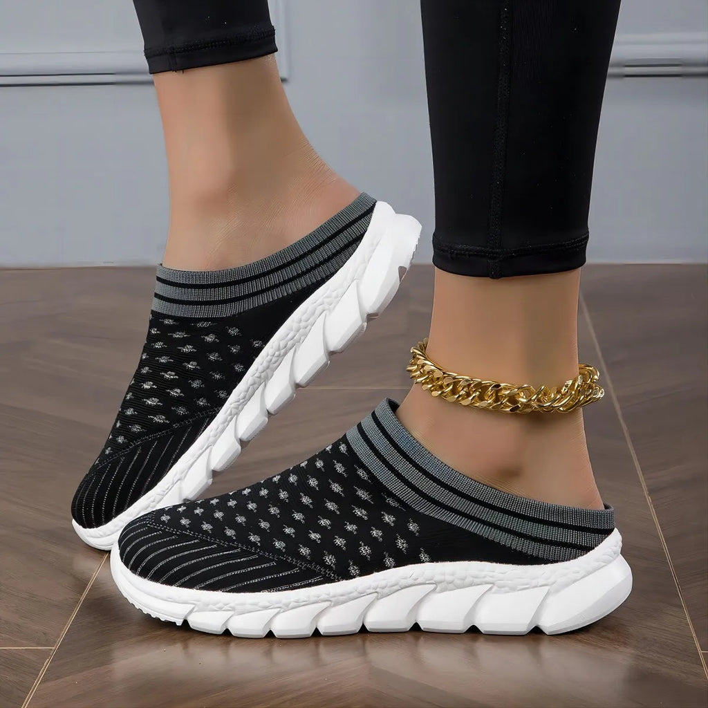 Women's black Flyknit slipper shoes with striped pattern and hollowed-out design on a white background.