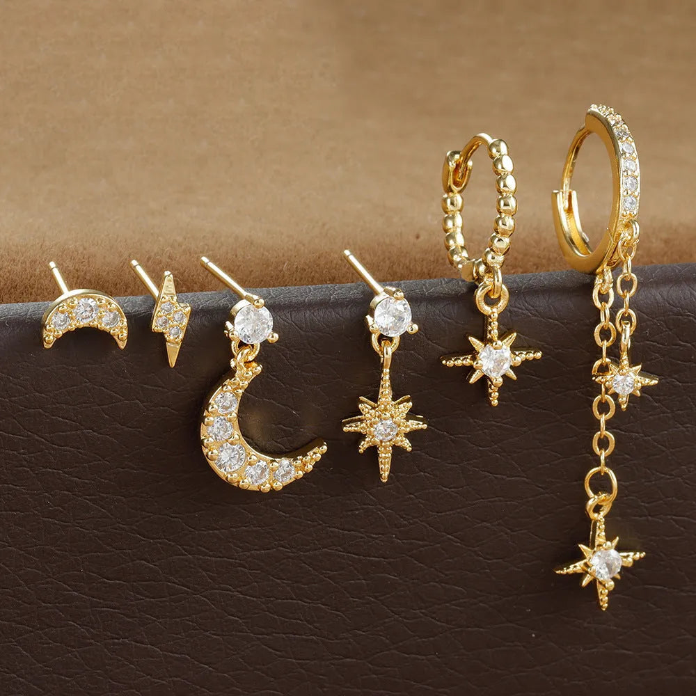 XINGX set of six gold chain tassel and zircon stud drop earrings laid out on a dark surface