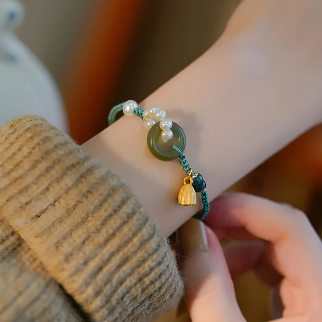 Close-up of a hand-woven flexible wire watch band with a pearl peace buckle closure.