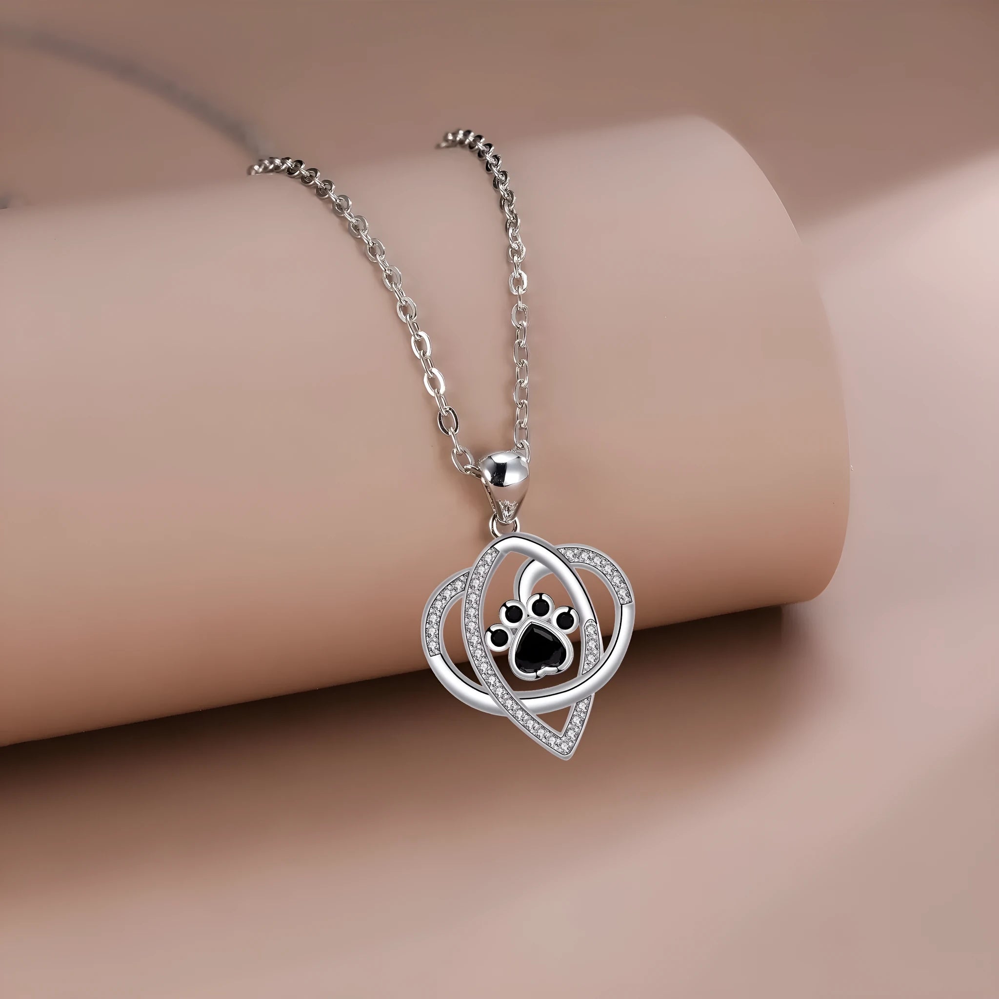 Copper pendant necklace showing cat and dog paw prints on a delicate cross chain.
