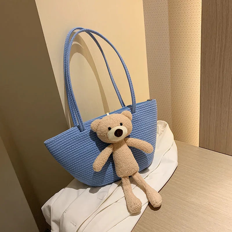 A woven dumpling-shaped shoulder bag in cotton and linen fabric with a three-dimensional front pocket.
