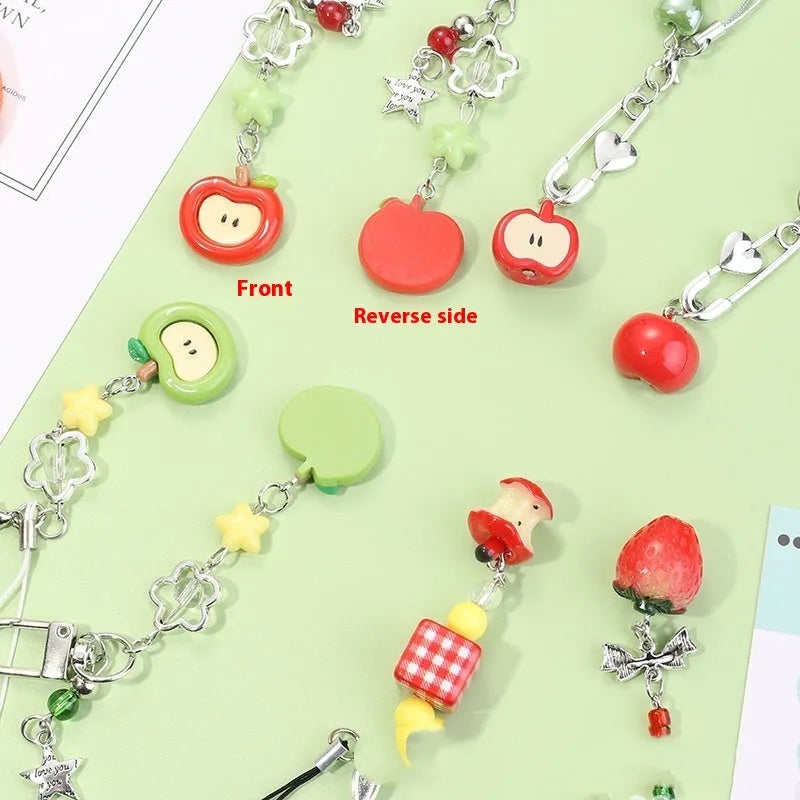 Red and green fruit-themed plastic mobile phone charm and keychain on a white background.