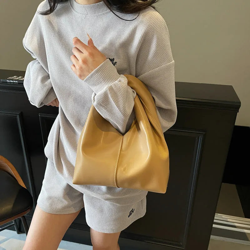 Dumpling-shaped women's handbag in various colours showing sandwich pocket design and fold-stitch details