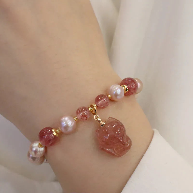Light pink freshwater pearl bracelet with a strawberry quartz fox charm on a metal chain.