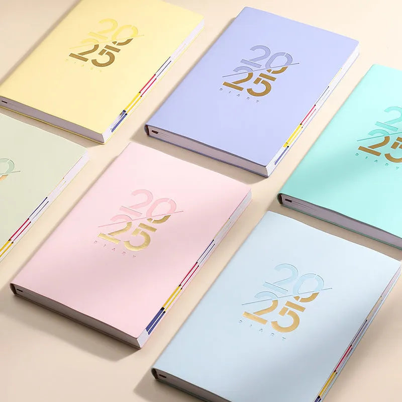 2025 A5 schedule book with faux leather cover in blue, showing open pages on a desk