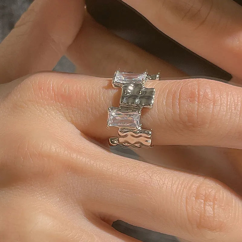 Silver geometric ring with open adjustable band and three-dimensional decoration, shown from multiple angles