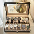 Grey leather watch storage box with see-through lid showing watch compartments