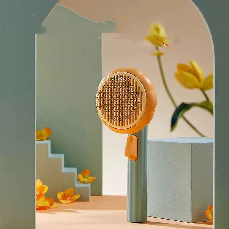 Pumpkin coloured hand-held pet grooming brush with stainless steel needles on a curved comb.
