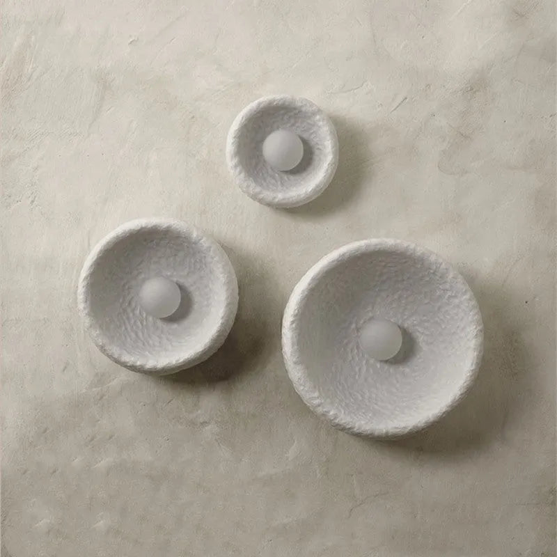 Japanese-style simple white resin wall lamp emitting warm light on a plain wall.