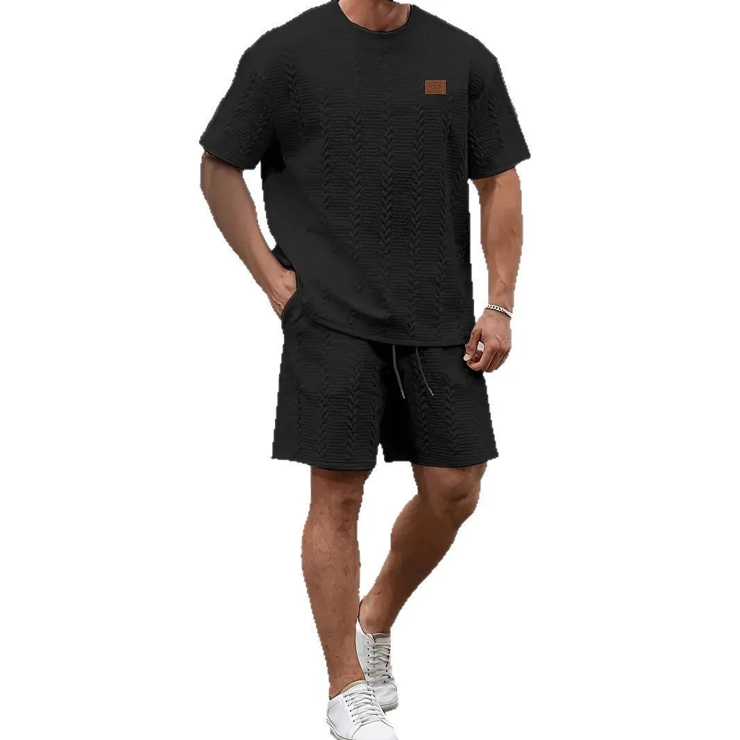Men's black polyester sports two-piece set with rib short sleeves and a patch design detail.