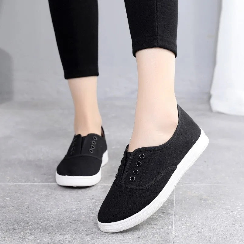 Low-top canvas sneakers in black, white, grey, and pink with a flat heel and cloth lining.