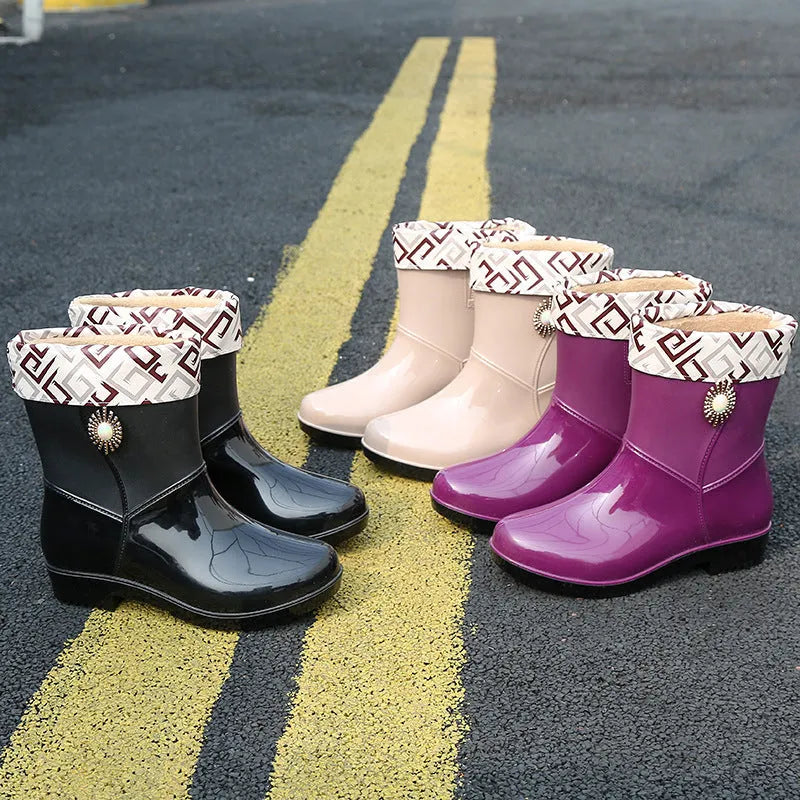 Women's purple PVC rain boots with a middle tube height and non-slip sole on a wet surface.