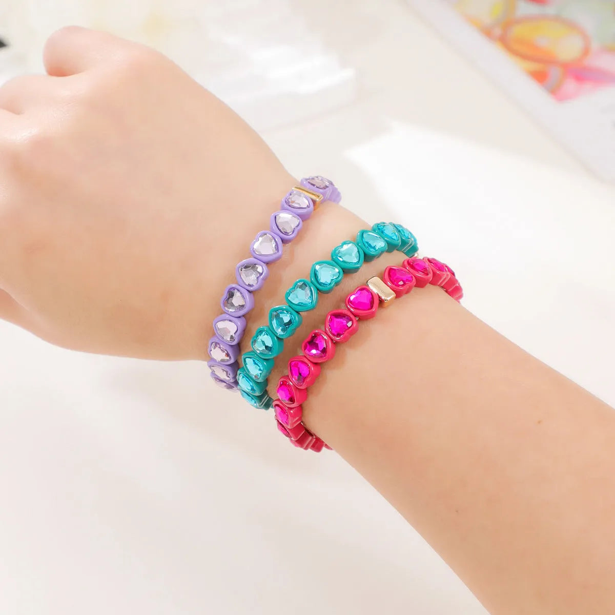 Colourful enamel heart charm on a stretch alloy bracelet.