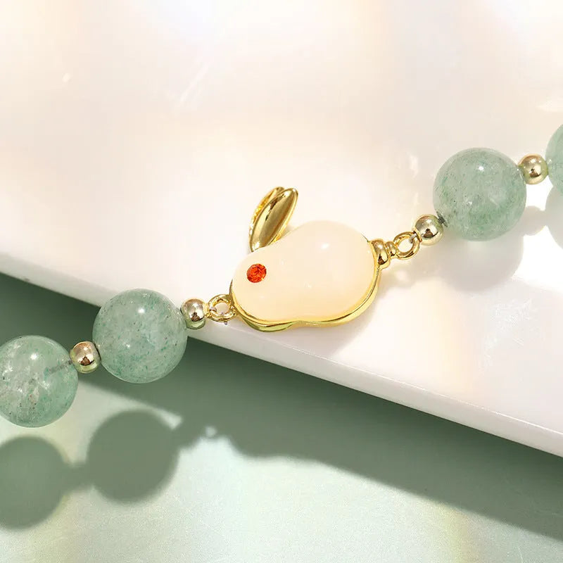 Women's rabbit charm bracelet with green aventurine and strawberry quartz beads, copper and gold details.
