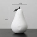 Simple resin apple and pear decoration in white, black, orange, or blue on a table.
