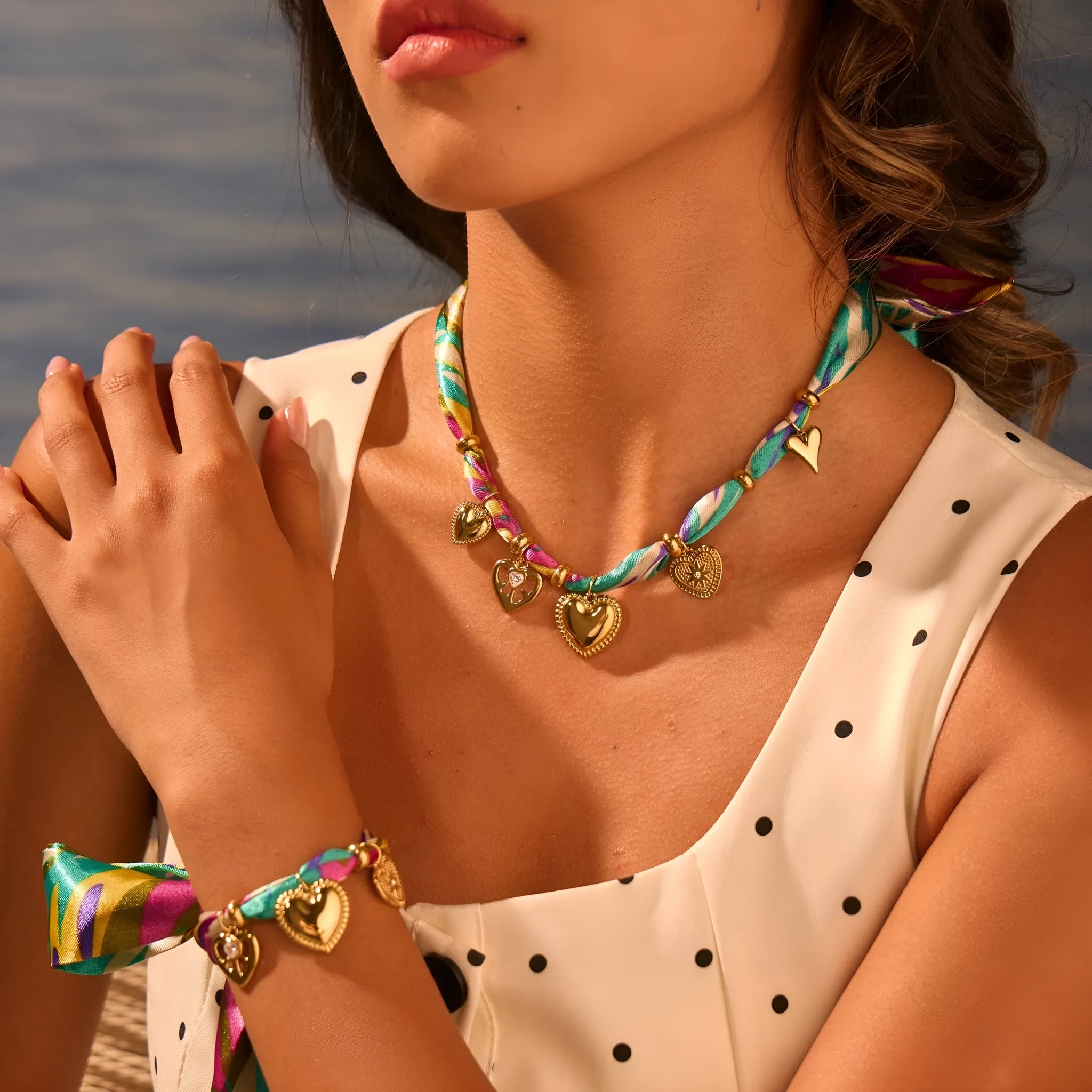 Geometric pendant on a stainless steel chain necklace next to a matching plated bracelet.