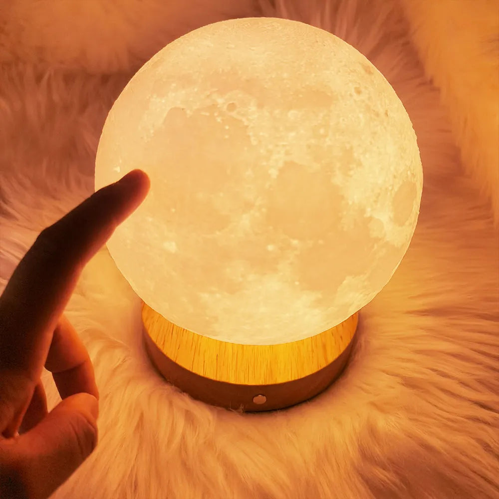 Rotating sleeping moon night lamp on a wooden base, showing three-colour light options.