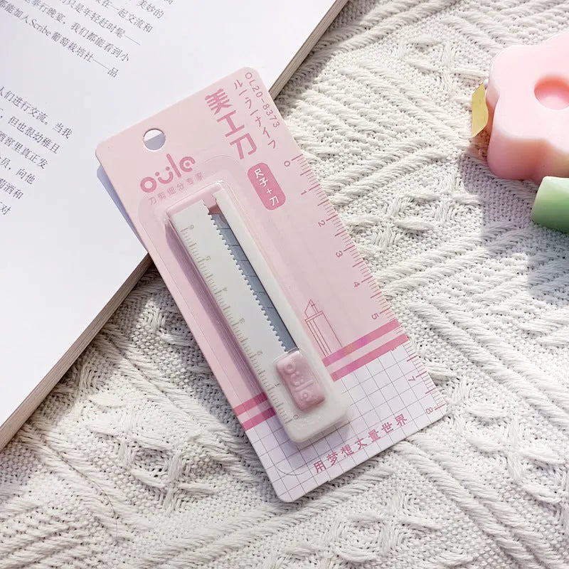 Small plastic-bladed art knife in blue, khaki, orange, pink, and purple colours, showing 7.2 cm size.