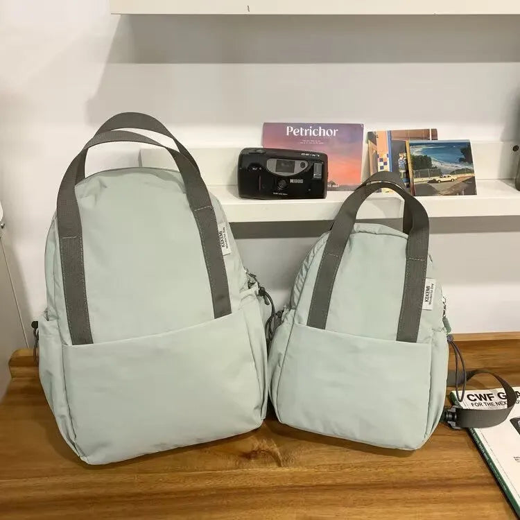 Simple solid colour nylon backpack shown in blue, with curved shoulder straps and a front lock.