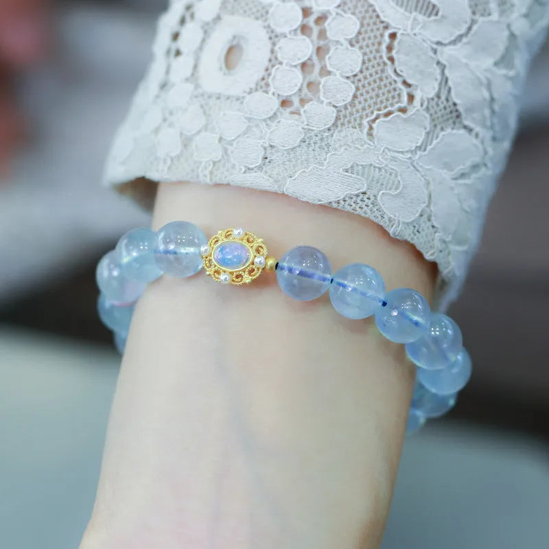 DIY aquamarine Fengjiu charm bracelet components laid out for assembly, showing pearls and pink crystals.