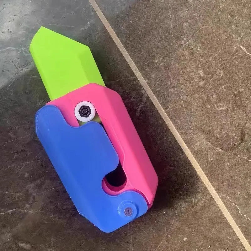 3D printed orange and green carrot-shaped gravity flick knife fidget toy on a white background.
