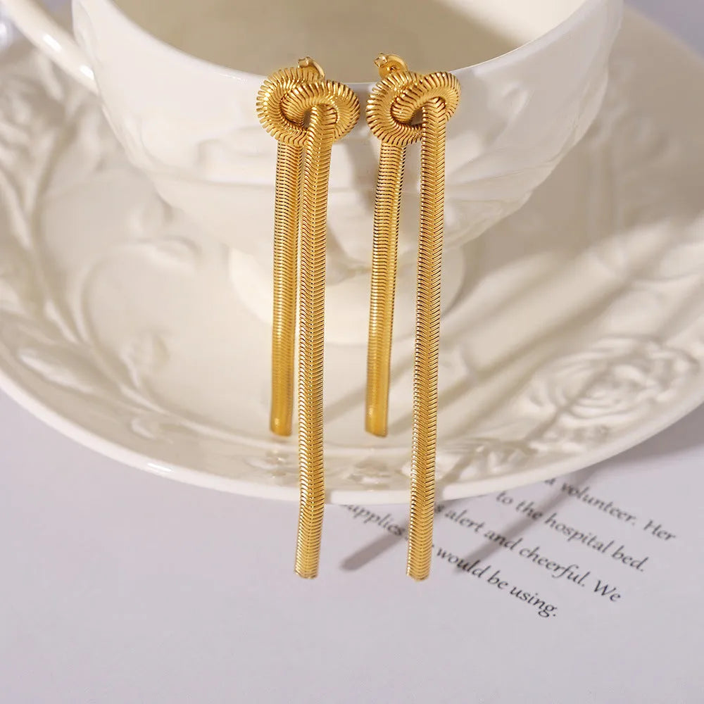 Gold titanium steel necklace with tassel pendant and matching earrings on dark background