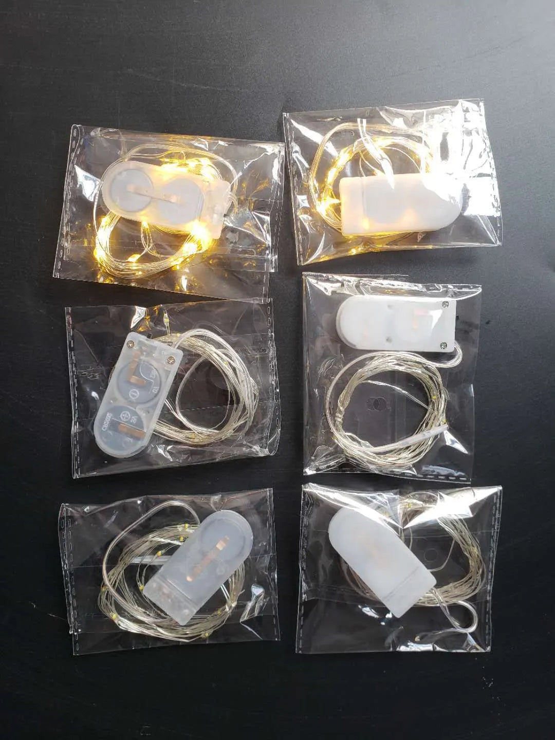 Close-up of a flexible copper wire LED light string with 20 small white LEDs and a white plastic CR2032 battery box.