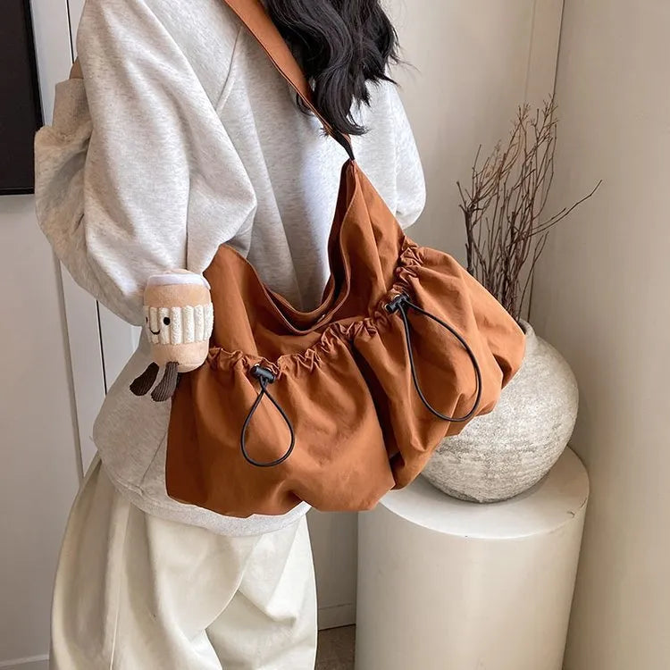 Green pleated crossbody bag with split pocket, folded to show 1cm thickness and mobile phone compartment inside