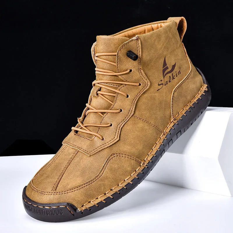 A pair of beige retro high-top casual leather boots with a round toe and elastic band fastening on a plain background.