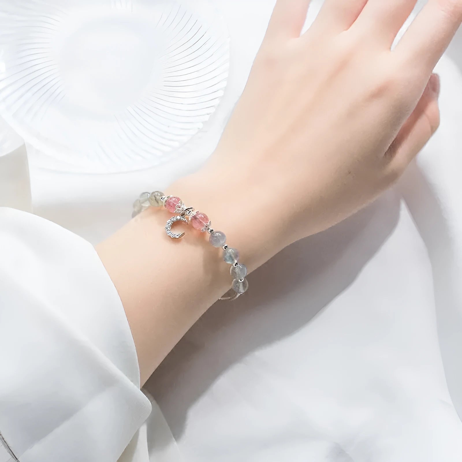 Handmade silver-tone adjustable bracelet with a moonstone bead and small crescent moon charm on a white background.