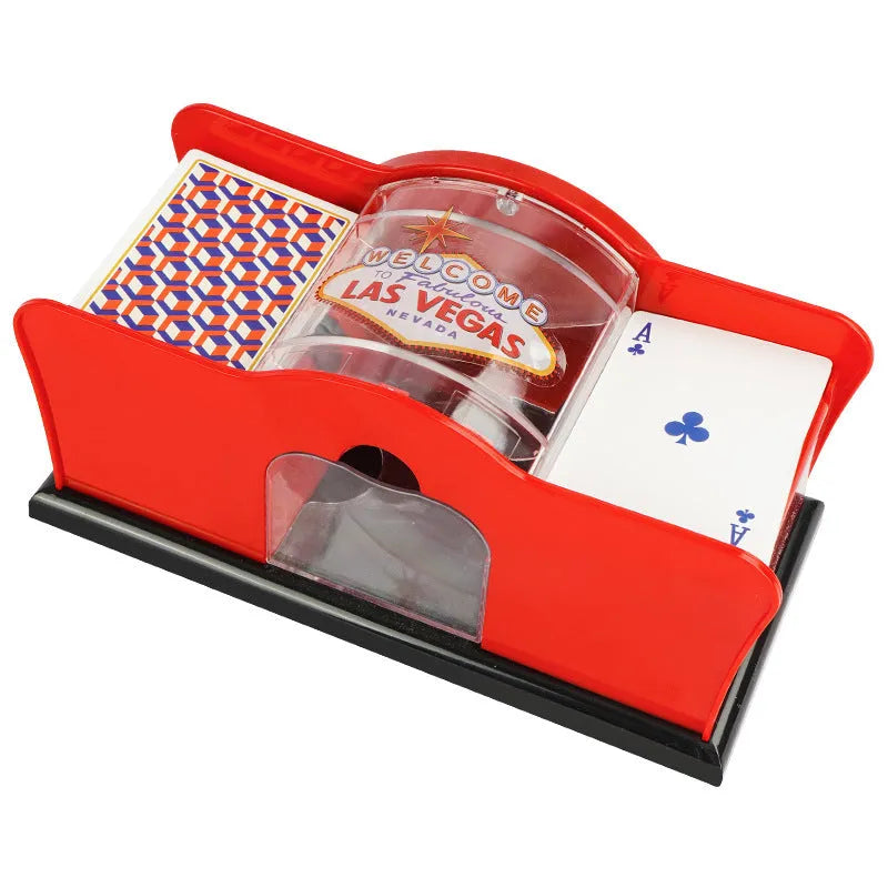 Black manual card shuffler with hand crank on a table next to playing cards.