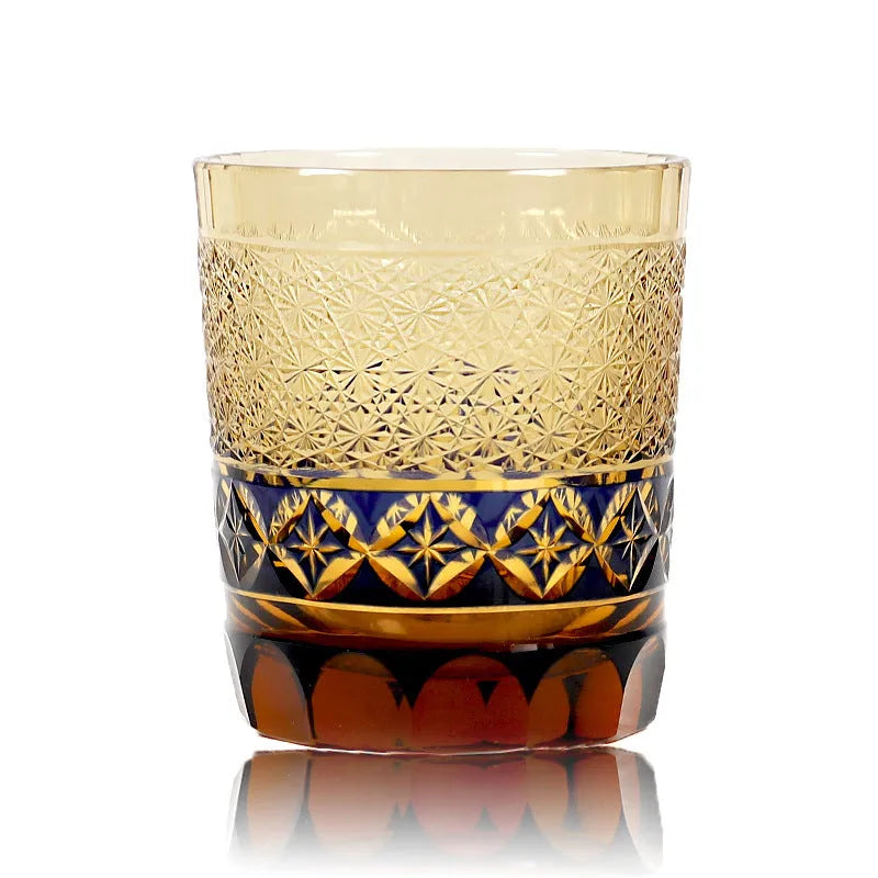 Hand carved Japanese style crystal whiskey glass in amber colour on a dark surface