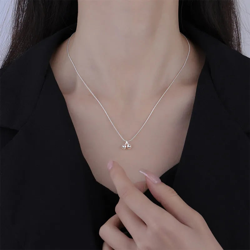 Silver cherry necklace with adjustable snake bone chain and detailed fruit pendant on a model