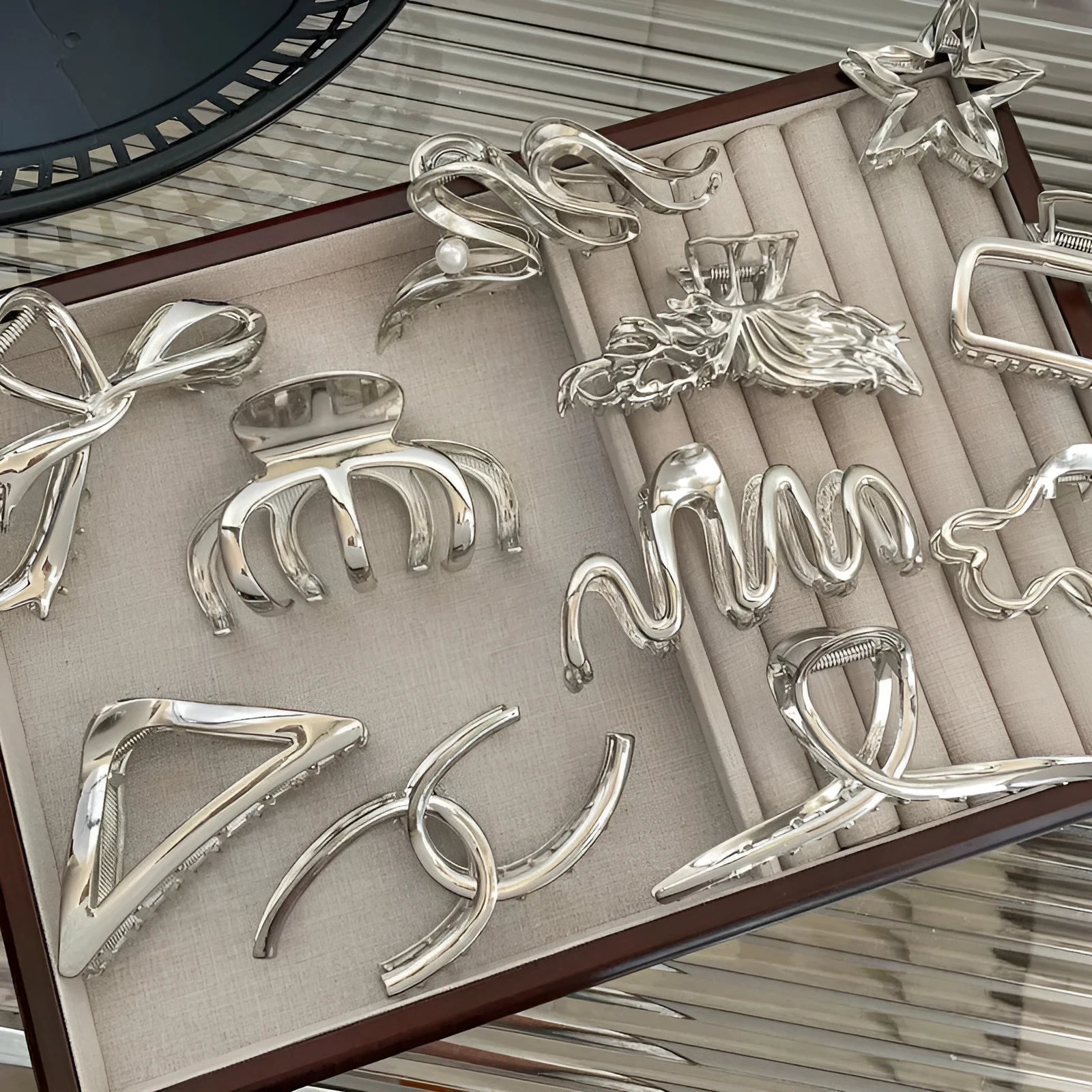 Assortment of silver metal hair claw barrettes in various shapes including waves, bows, and crosses.
