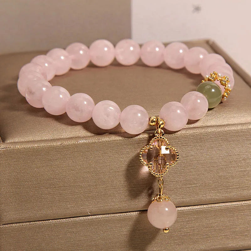 Pink crystal bracelet with four-leaf clover pendant and rhinestone details