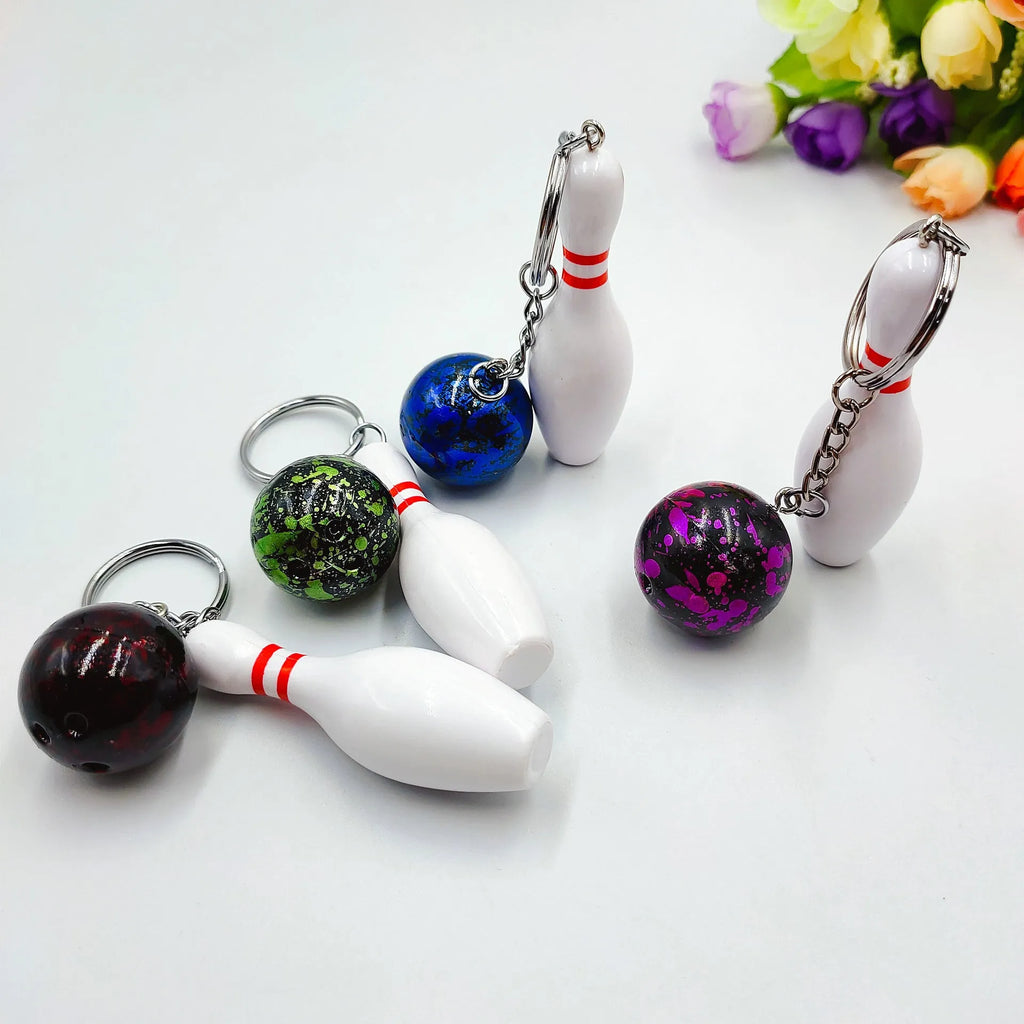 Mini bowling pin keychain pendant in four colours: dark red, blue, purple, green, showing PVC metal construction