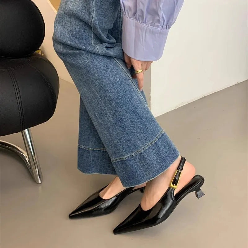 Women's black leather pointed toe shoes with a thin ankle strap and a low block heel.