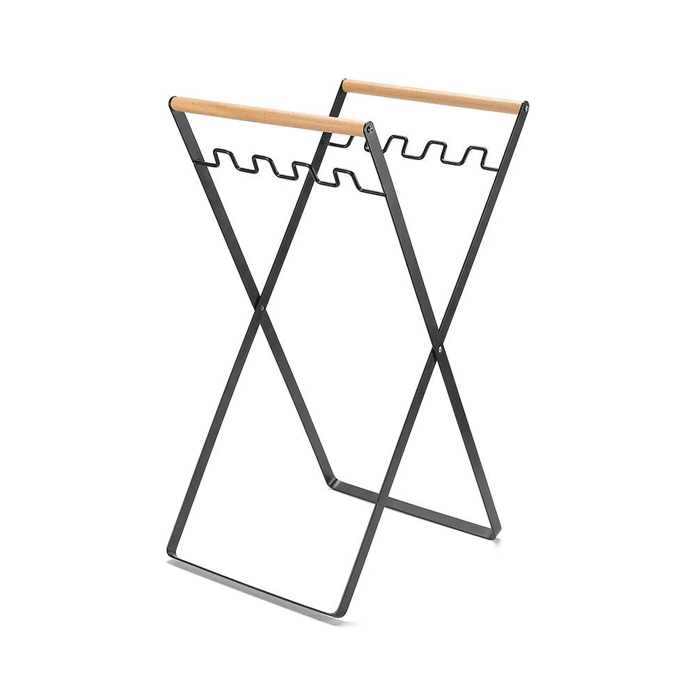 Black folding iron trash rack with wood handle holding bin bag outdoors