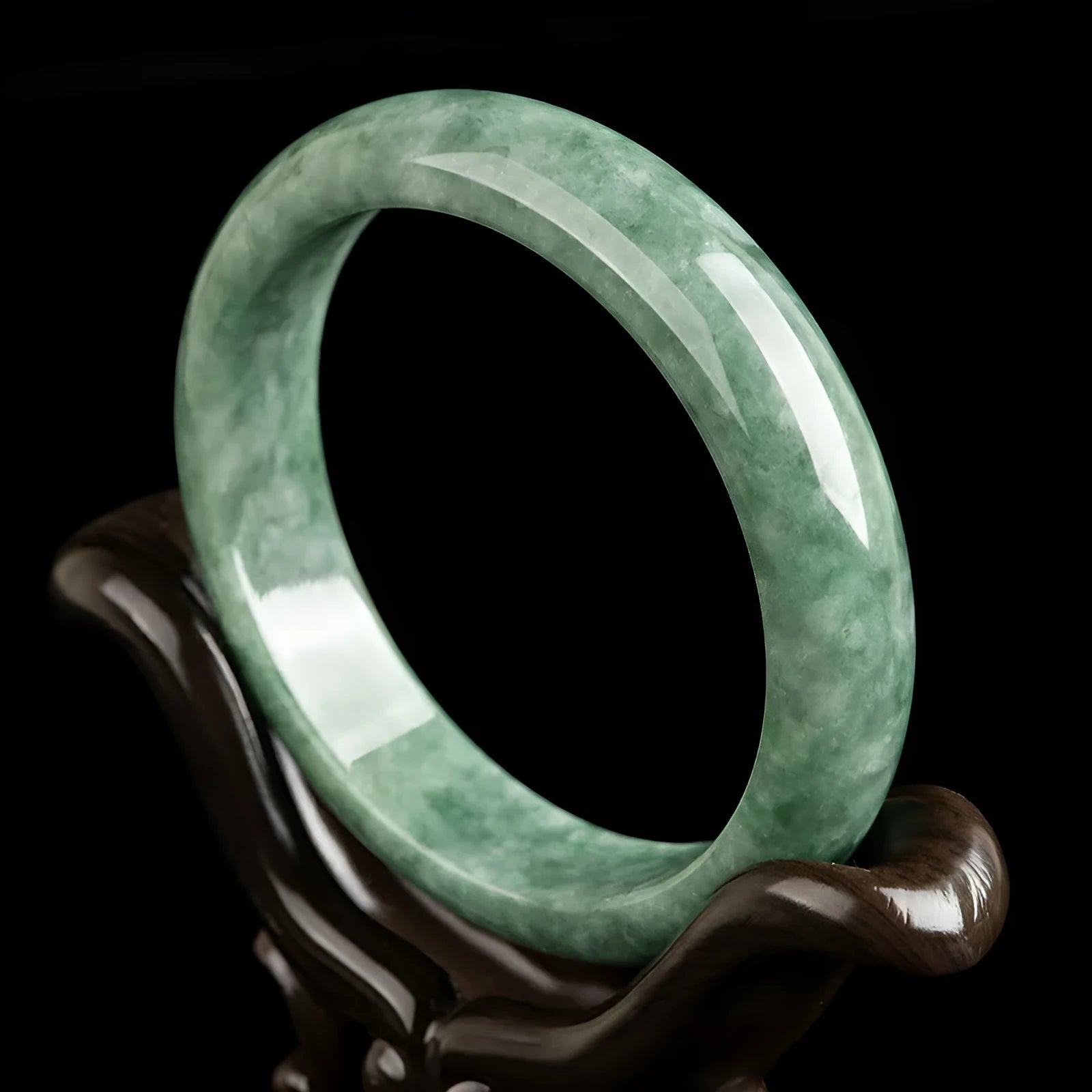 Women's simple bracelet with a natural green emerald bean gemstone on a wrist.