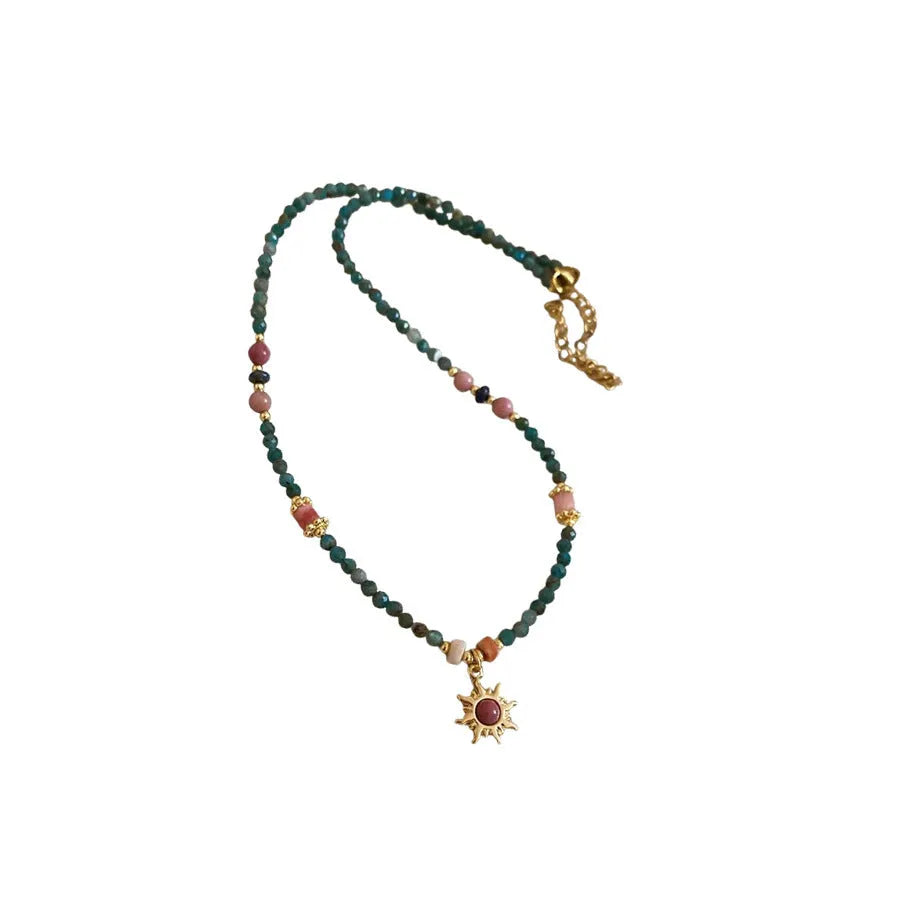Freshwater pearl necklace with a blue stone sun pendant on a delicate clavicle chain.