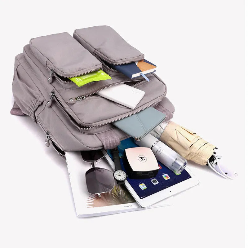Large purple waterproof travel backpack showing front organiser pocket and internal laptop and camera compartments.