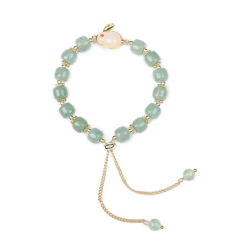 Women's rabbit charm bracelet with green aventurine and strawberry quartz beads, copper and gold details.